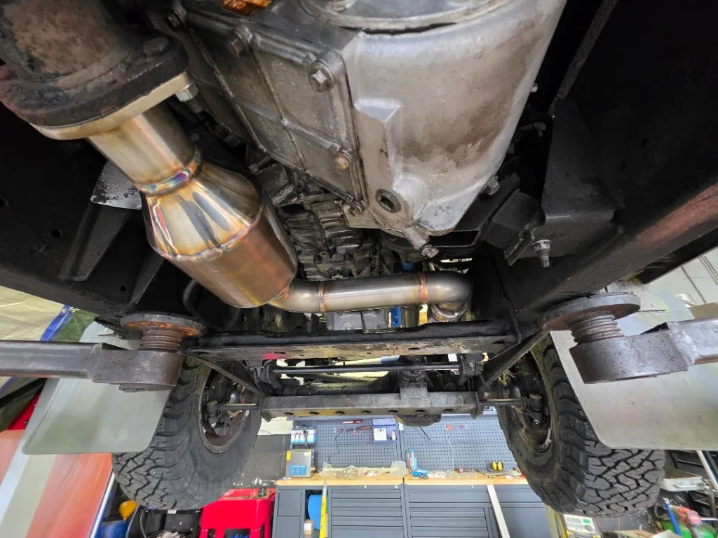 Gemonteerde RVS downpipe onder Land Rover Defender op de brug